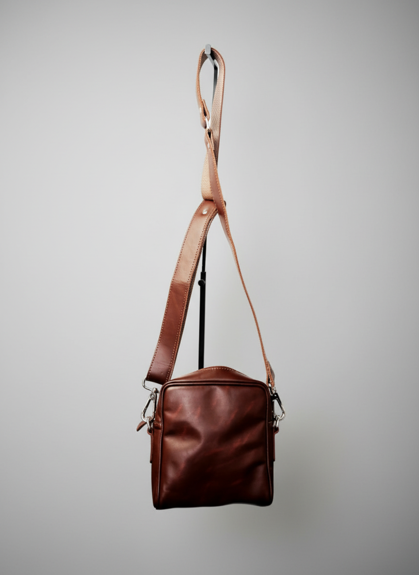 Brown leather bag with a strap on a white background
