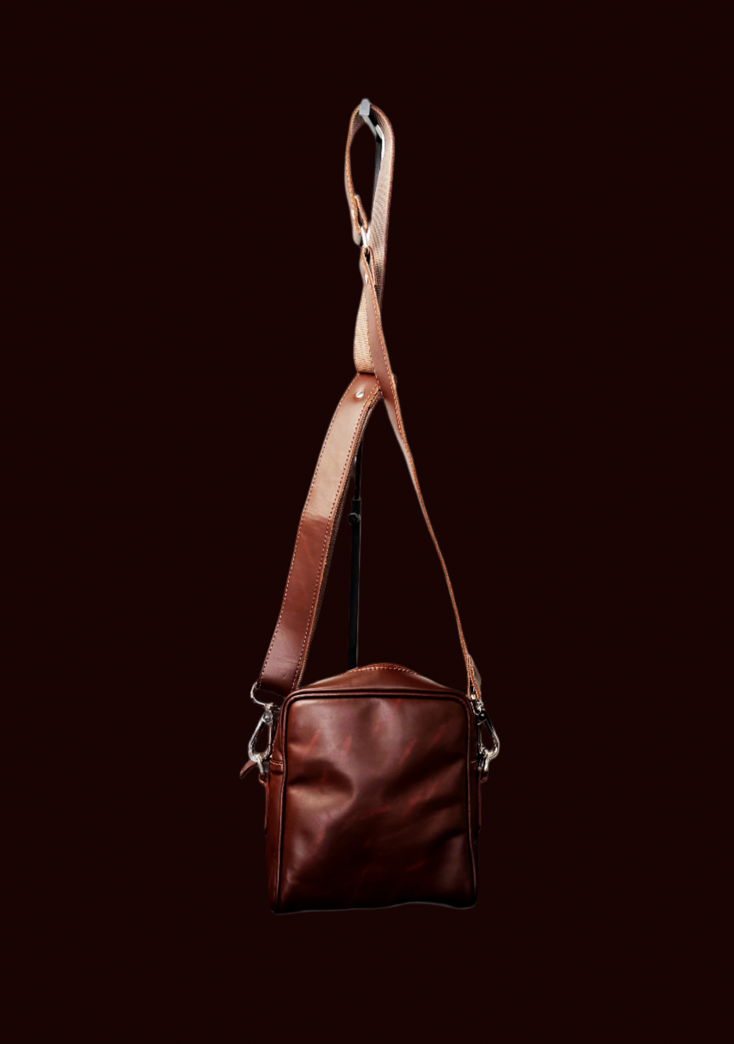Brown leather bag with a strap on a white background