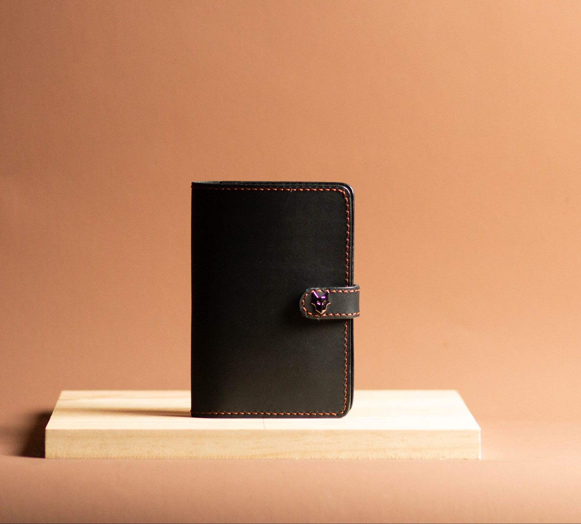 Black leather notebook with a strap on a beige surface and background