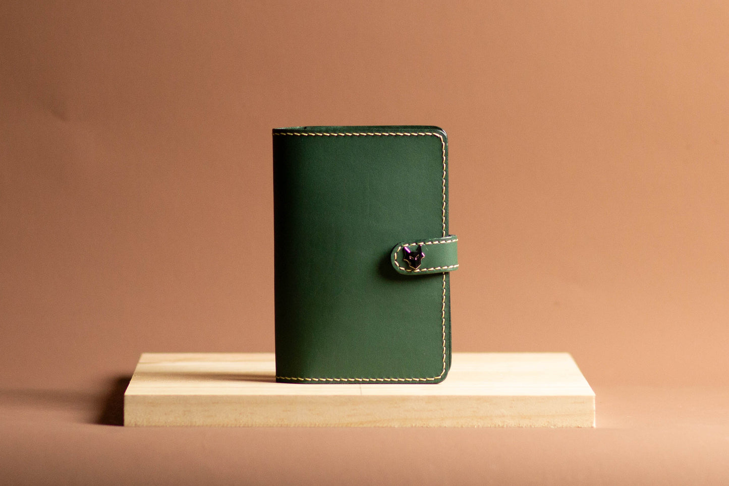 Green leather passport holder wallet on a wooden stand with a brown background